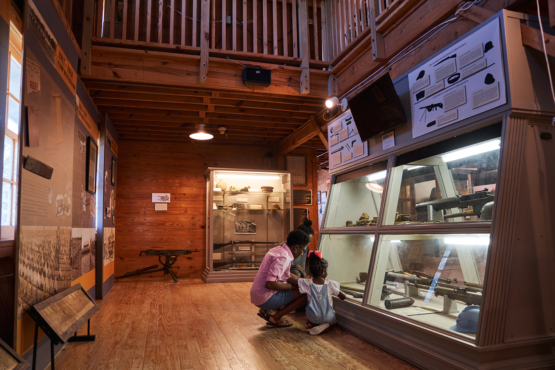 A parent and child kneel in front of a display of military artifacts at Louisiana Maneuvers and Military Museum in Pineville.