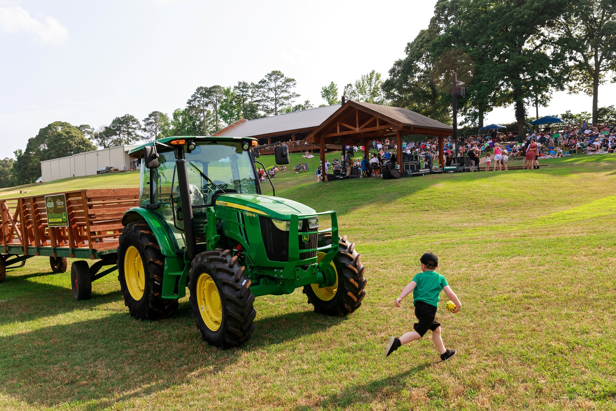 Wine at Landry's A child runs next to a tractor while families enjoy an outdoor concert in the background.