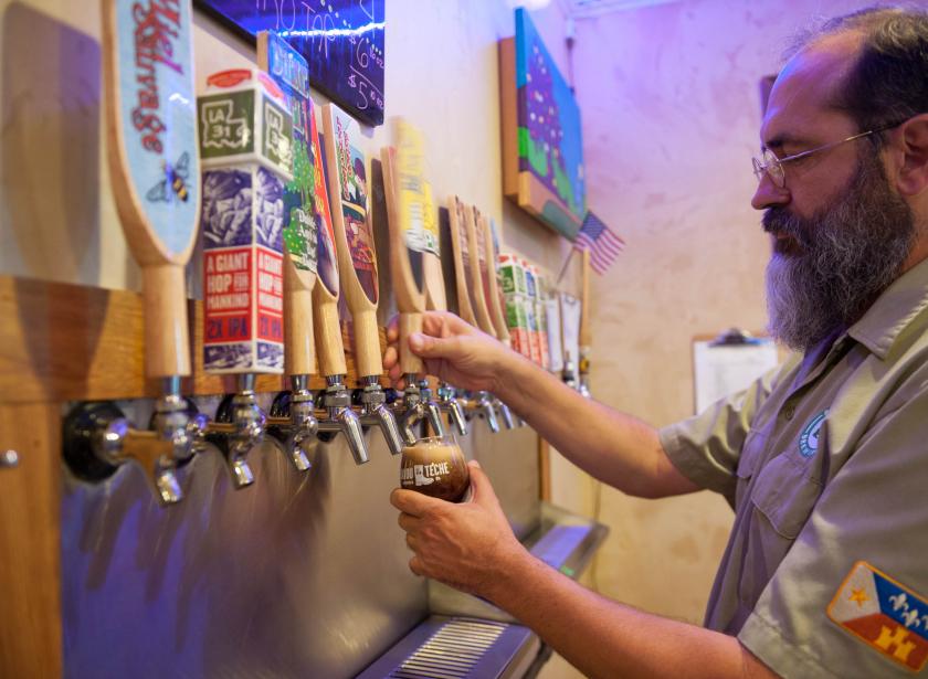 Bayou Teche Brewing Company Bartender pouring a beer into glass from colorful taps at Bayou Teche Brewery in Arnaudville, Louisiana.